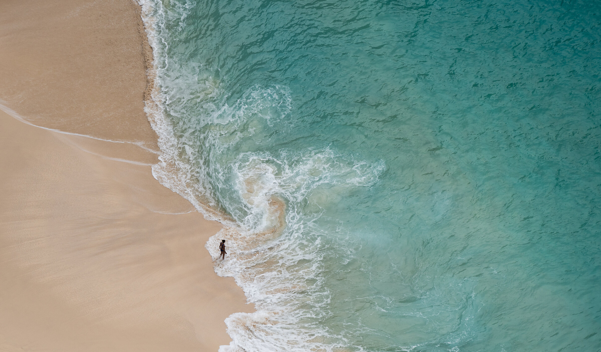 Turquoise waves washing onto a sandy beach in Bali.
