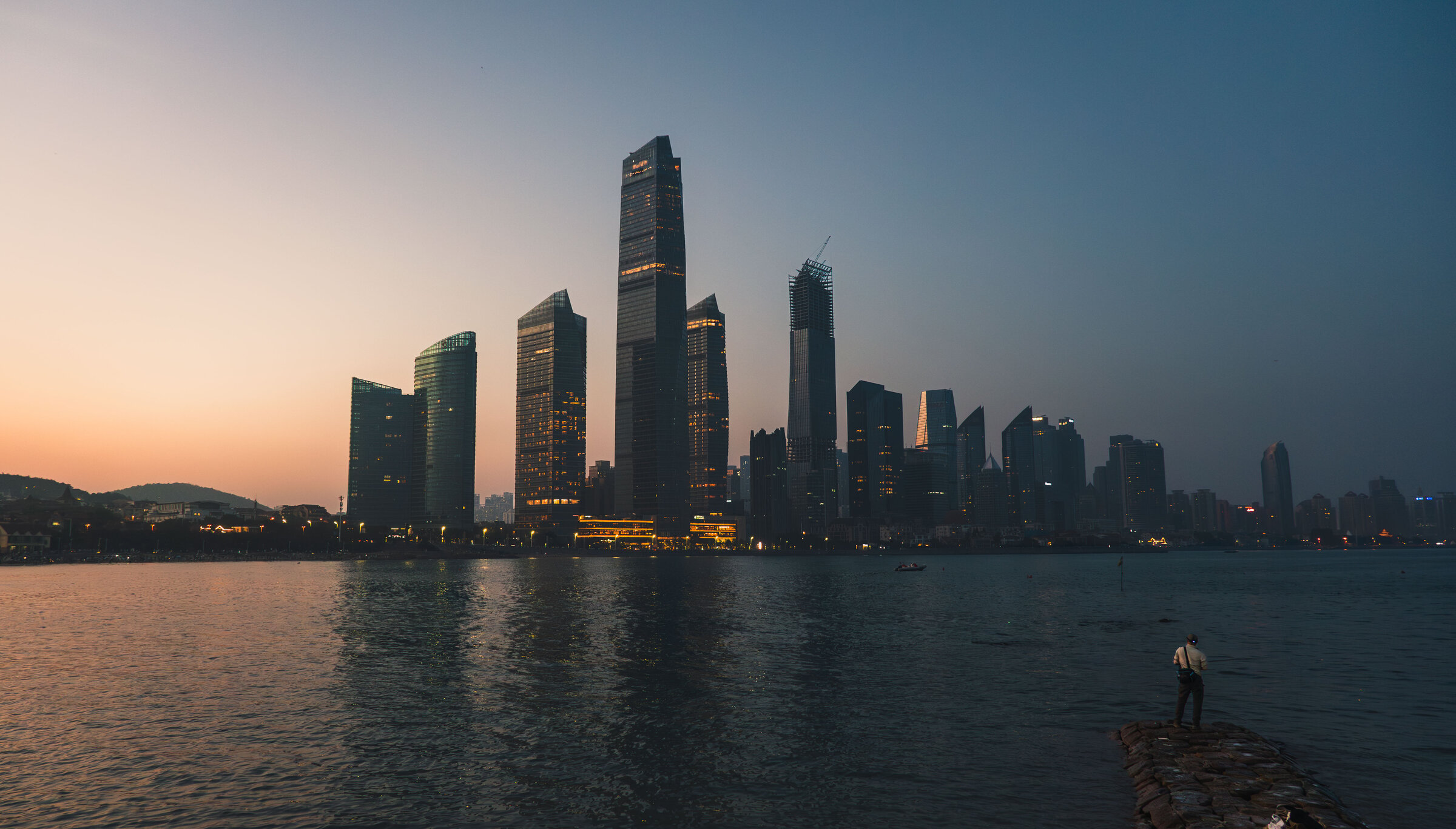 Qingdao waterfront towers silhouetted against the sunset.