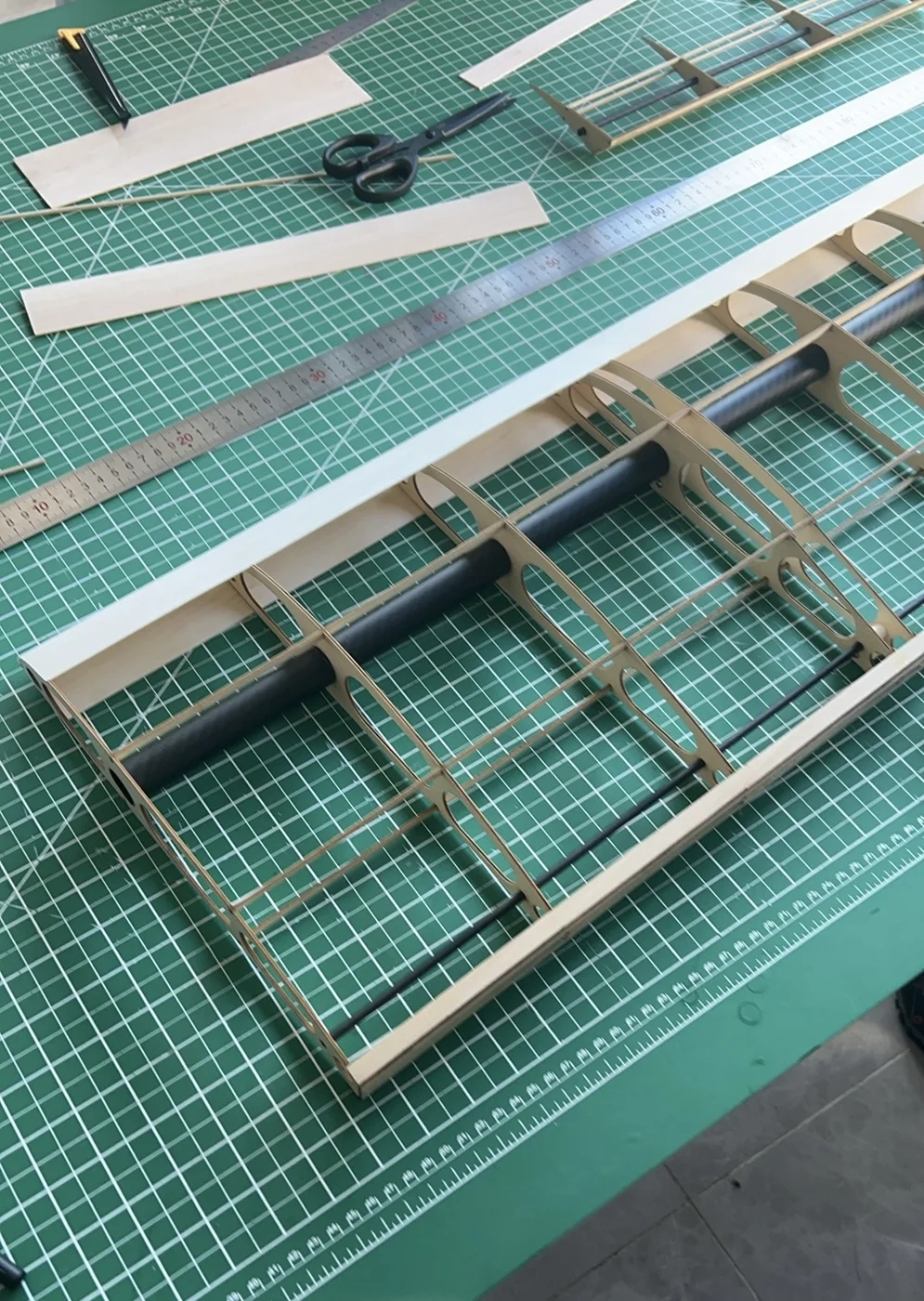 Partially assembled built-up aircraft wing skeleton on a cutting mat